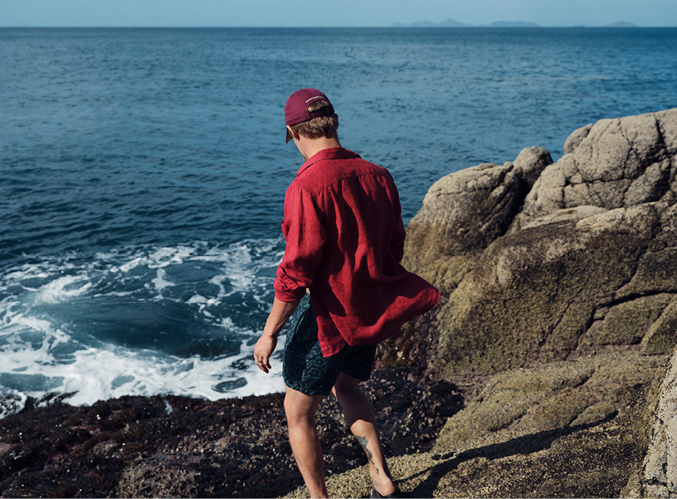 Man in red linen shirt walking on the coast