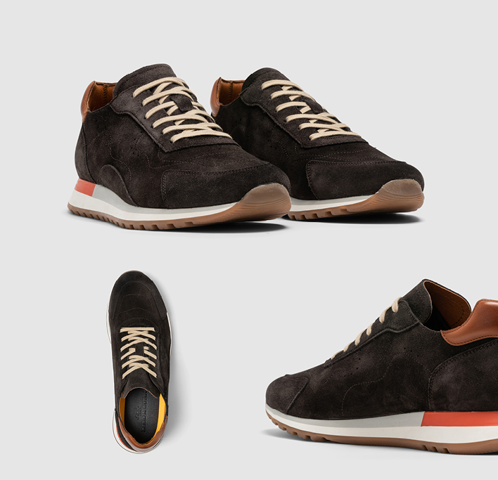Men's black suede sneaker with tan laces and white, grey and orange sole.