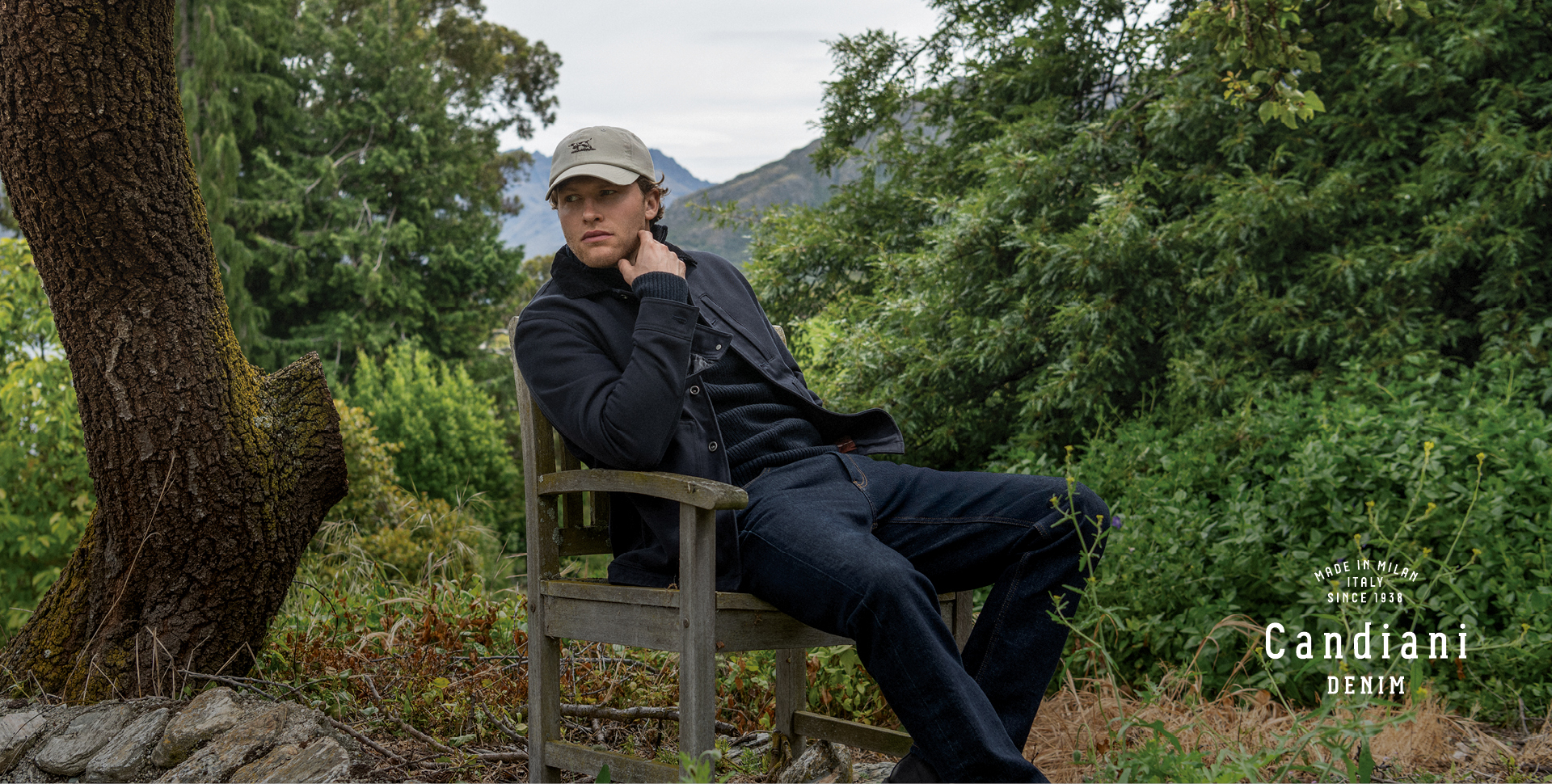 Man sitting in chair outside in tree setting.