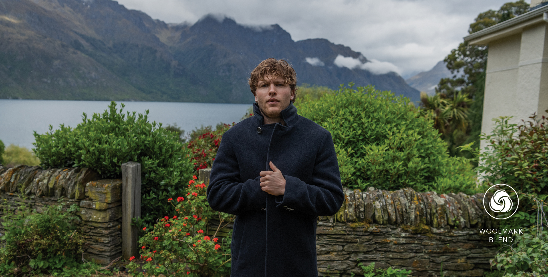 A man in a stylish coat stands outside a house, adding character to the picturesque setting.